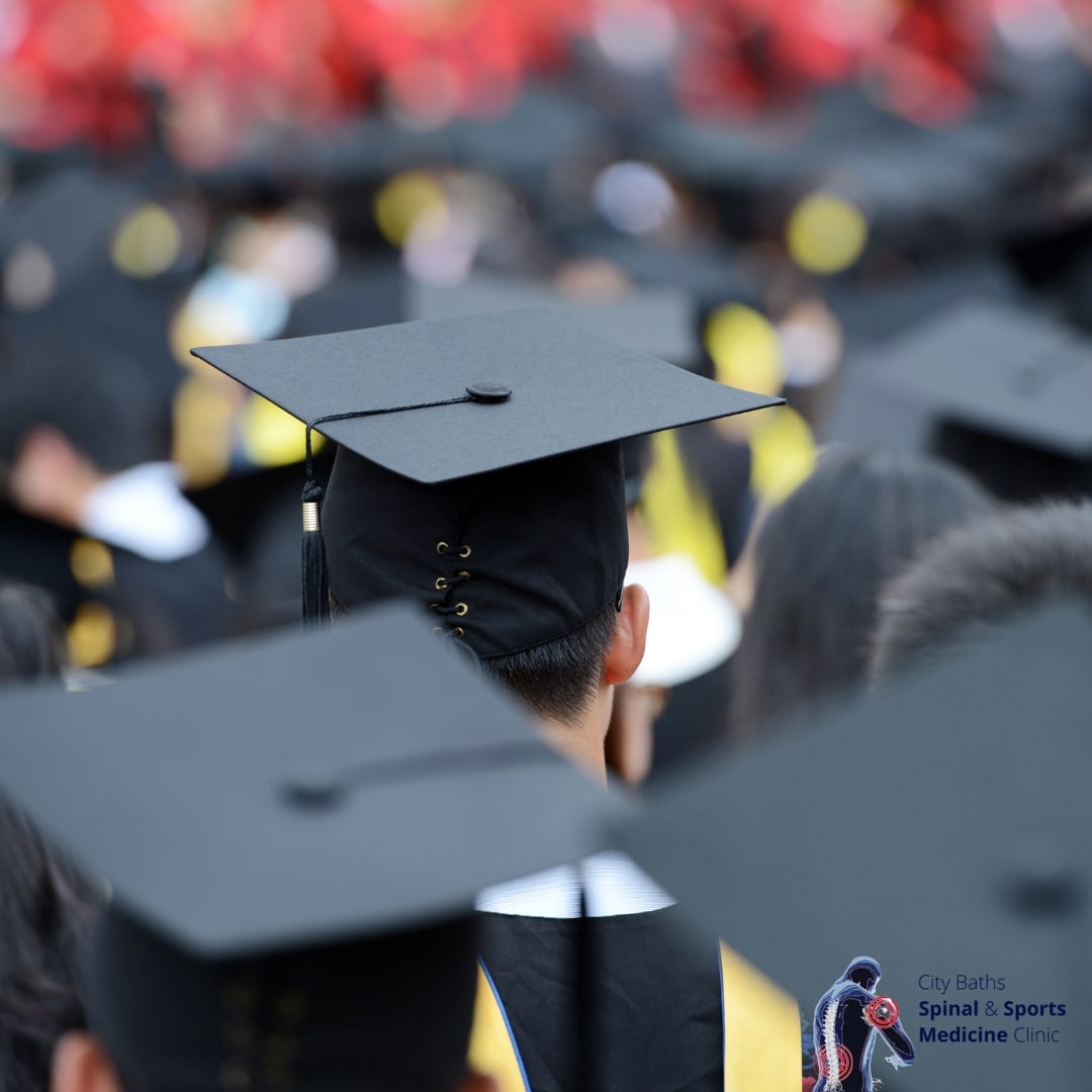 A crowd of university graduates pictured from behind, wearing their graduation caps.